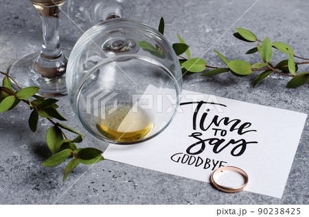 Time to say goodbye. The inscription on a white paper sheet. White wine in a glass glass. Gold engagement ring. Concept - deterioration of relations between people 90238425