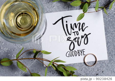 Time to say goodbye. The inscription on a white paper sheet. White wine in a glass glass. Gold engagement ring. Concept - deterioration of relations between people 90238426