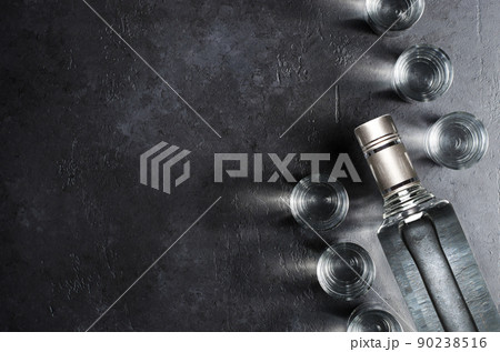 Bottle of vodka. Vodka in glass glasses. Dark black background. Copy space 90238516