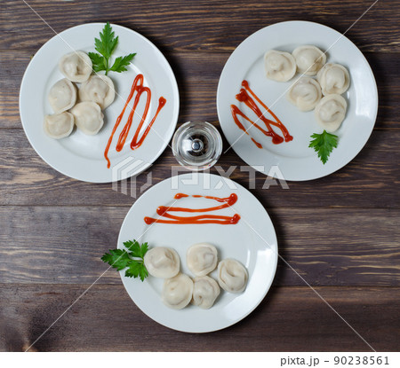 Traditional Russian dumplings, ravioli, dumplings on a white plate with red sauce and parsley. Dark wooden background. 90238561