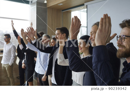 Joyful listeners of business conference raise their hands to ask questions to speaker or to vote. 90239342