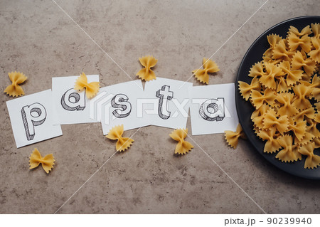 Lettering with Handful of Pasta Laid Up on the Black Plate on the Table 90239940