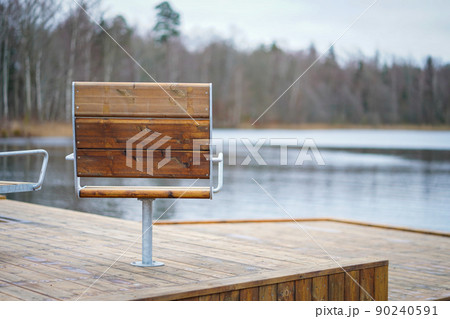 Metal with wooden cover modern chairs at the relaxation area in front of the lake 90240591