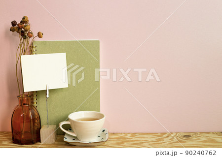 Memo holder and notebook, cup of tea, dry flowers on wooden desk. pink wall background. workspace 90240762