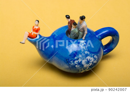 Group of miniature people figures standing in the teapot 90242007