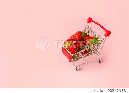 Fresh red strawberry in shopping cart on pink background. Online shopping and Valentines Day minimalistic concept. Black Fridays sales banner. Healthy, organic, vegan food Fresh red strawberry in shopping cart on pink background. Online shopping and Valentines Day minimalistic concept. Black Fridays sales banner. Healthy, organic, vegan food 90242388
