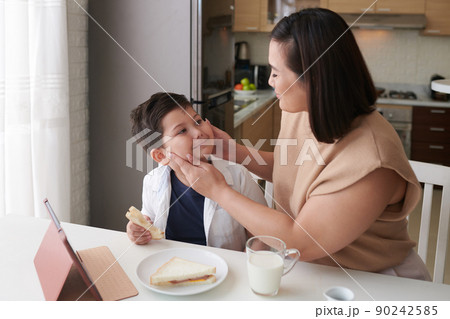 Mother squishing Chubby Cheeks of Son 90242585