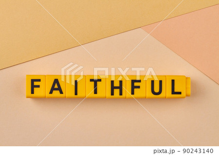 The word faithful written on yellow cubes close up. Remaining loyal and steadfast. 90243140