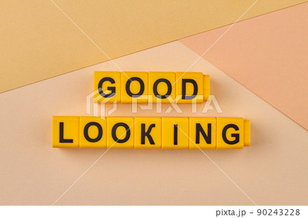 The inscription good looking written on yellow cubes against light background. 90243228