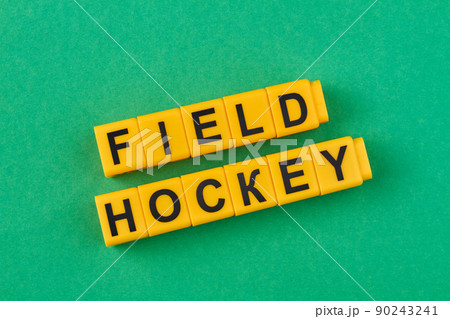 The inscription field hockey written on yellow cubes against green background. 90243241