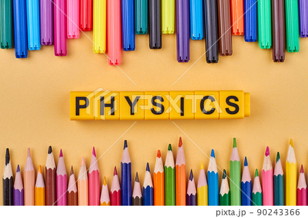 Word physics written on yellow cubes in frame from colorful school supplies. 90243366