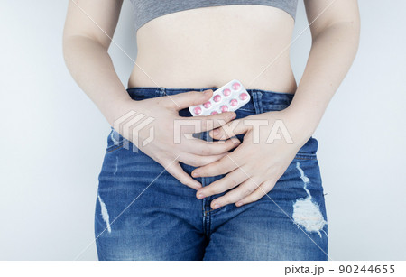 Tablets for pain during menstruation. Pain during menses. The concept of critical days for a woman. The girl stands on a white background and holds medicines for pain in her hands. Painkillers Tablets for pain during menstruation. Pain during menses. The concept of critical days for a woman. The girl stands on a white background and holds medicines for pain in her hands. Painkillers 90244655