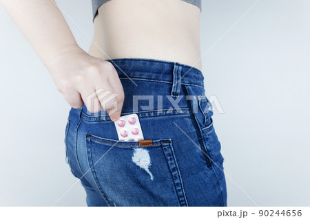 Tablets for pain during menstruation. Pain during menses. The concept of critical days for a woman. The girl stands on a white background and holds medicines for pain in her hands. Painkillers 90244656