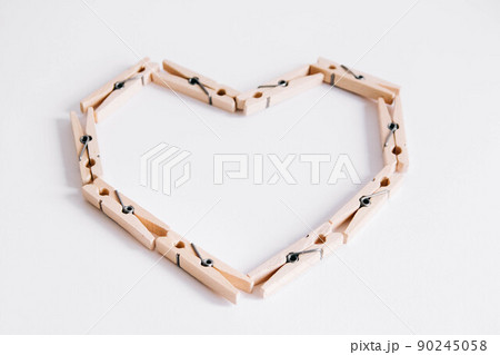 Wooden clothespins on white background which are folded in the form of heart icon. View from above. 90245058