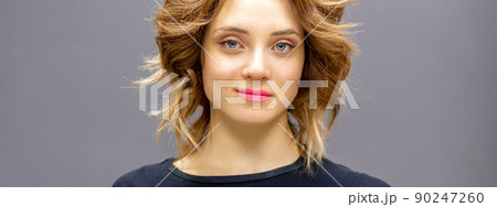 Portrait of a beautiful young caucasian red-haired woman with short wavy hairstyle smiling and looking at camera on dark gray background with copy space Portrait of a beautiful young caucasian red-haired woman with short wavy hairstyle smiling and looking at camera on dark gray background with copy space 90247260
