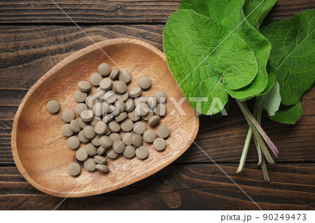Burdock leaves and pills with extract of arctium lappa. Top view. 90249473