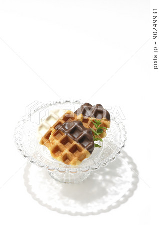透明なガラス製のケーキスタンドに盛り付けられているチョコがコーティングされたワッフルを白背景で撮影 透明なガラス製のケーキスタンドに盛り付けられているチョコがコーティングされたワッフルを白背景で撮影 90249931