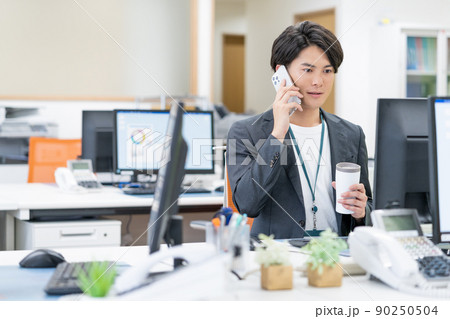 SDGs オフィスでタンブラーで飲み物を飲む若いビジネスマン 90250504
