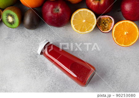 Various fruits and freshly squeezed fruits juice in bottle on gray background 90253080