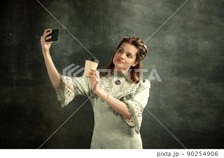 Emotional young beautiful girl, actress in image of medieval person posing isolated on dark background. Comparison of eras concept, flemish style. Art, beauty 90254906