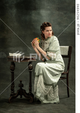 Comic portrait of young beautiful girl in gray dress of medieval style isolated on dark background. Comparison of eras concept, flemish style. Art, beauty 90254940
