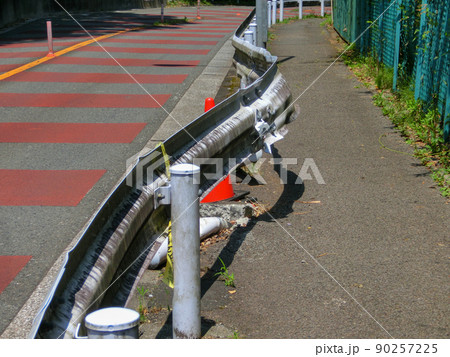 道路の歩道側に大きく曲がったガードレール 90257225