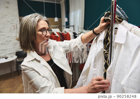 Mature European woman fashion designer stylist couturier tailor in a clothing design workshop and tailoring atelier with boutique Mature European woman fashion designer stylist couturier tailor in a clothing design workshop and tailoring atelier with boutique 90258248
