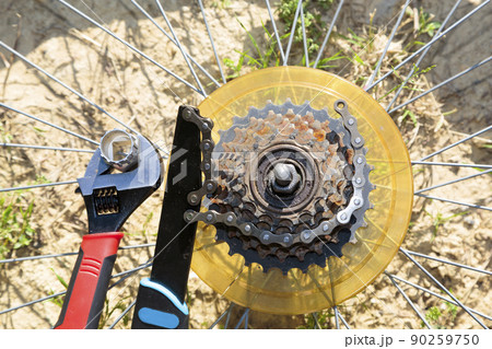 Old bicycle's rusty gears next to repair tools 90259750