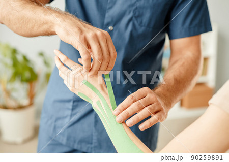 Therapist Putting Physio Tape on Hand 90259891
