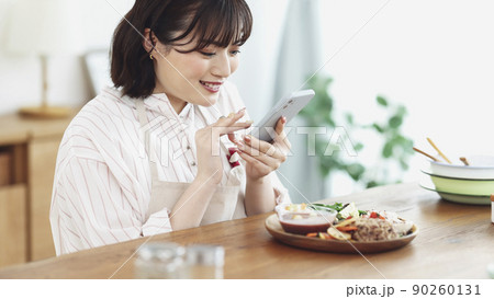 スマホで料理を撮影する若い女性 90260131