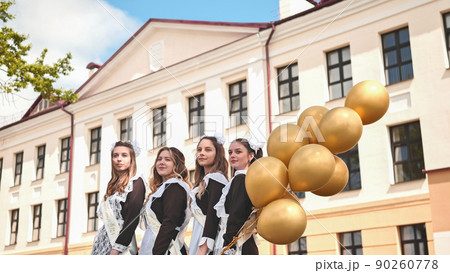 Cheerful Russian girls graduating with orange balloons on the last school day. 90260778