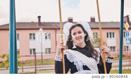Happy female graduate goes for a swing on the last day of school. 90260848