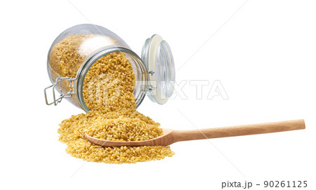 dry bulgur in wooden scoop and in glass storage jar isolated on white background. dry bulgur in wooden scoop and in glass storage jar isolated on white background. 90261125