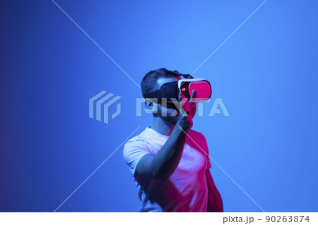 Man in vr glasses, playing video games with virtual reality headset. Trying to touch something with hand. Metaverse. 90263874