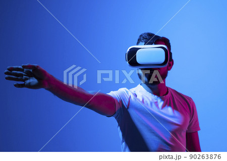 Young bearded man in virtual reality helmet plays online game in metaverse. Game simulates behavior in fictional world, gadgets and virtual reality addiction. Future technology concept. 90263876