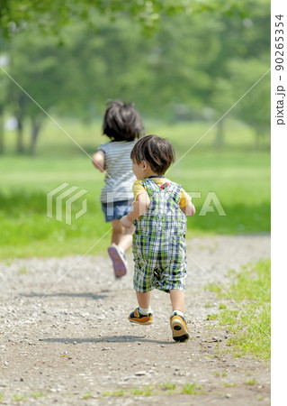 新緑の公園で遊ぶ姉と弟の後ろ姿 90265354