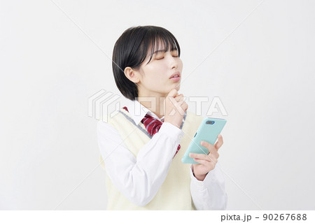 白背景でスマホを持って悩む女子高生 白背景でスマホを持って悩む女子高生 90267688