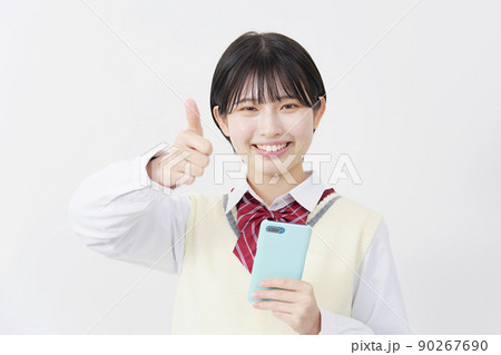 白背景でスマホを持ってグッドサインする女子高生 90267690
