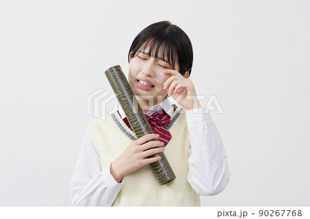 白背景で卒業証書の筒を持って泣く女子高生 90267768