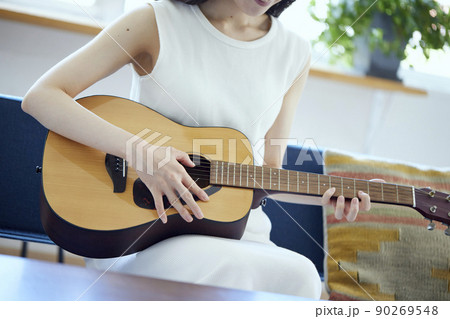 ソファーでギターを弾く日本人女性 90269548