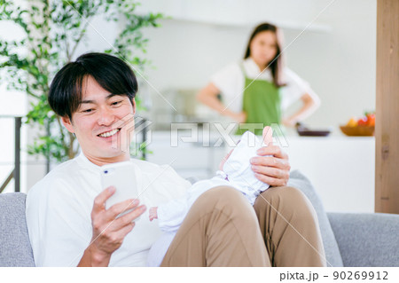 スマホを見ながら赤ちゃんを抱く男性と怒る女性(夫婦) スマホを見ながら赤ちゃんを抱く男性と怒る女性(夫婦) 90269912