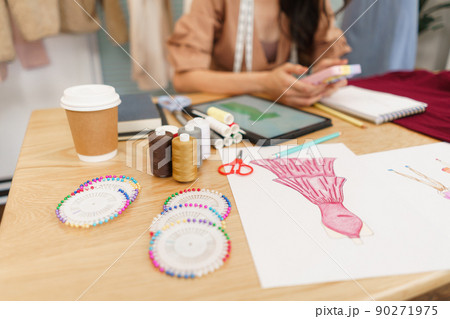 Fashion design concept, Asian female tailor use phone for relax after sketch new clothes collection Fashion design concept, Asian female tailor use phone for relax after sketch new clothes collection 90271975