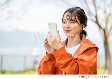 晴れた公園でスマホを操作する若い女性 90273392