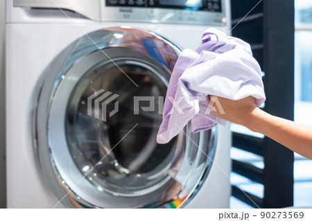 Housewife Woman hand holding clothes inside Washing Machine in laundry room 90273569