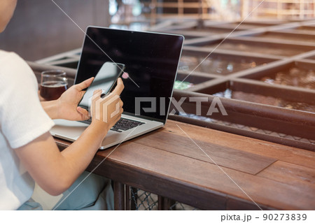 Casual Businesswoman using smartphone and laptop, freelance woman typing keyboard computer notebook in cafe or modern office. technology, digital online and network concept 90273839