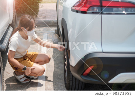 Woman driver hand inflating tires of vehicle, removing tire valve nitrogen cap for checking air pressure and filling air on car wheel at gas station. self service, maintenance and safety 90273955