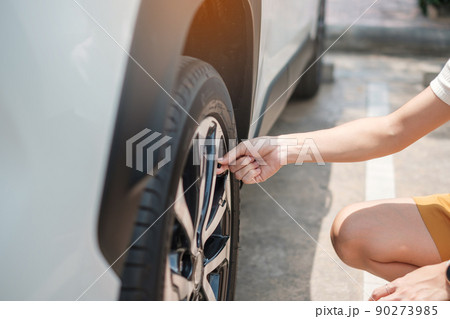 Woman driver hand inflating tires of vehicle, removing tire valve nitrogen cap for checking air pressure and filling air on car wheel at gas station. self service, maintenance and safety 90273985