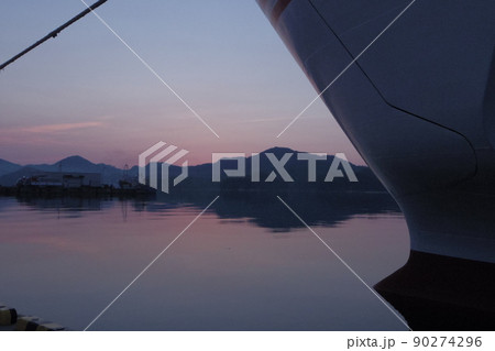 隠岐島西郷港フェリー埠頭の夜明け　船首の先、東の空が僅かに赤くなる日の出直前　鏡の様な無風の海面 90274296