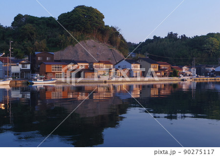 日の出の漁村　静かな海に映る漁村の街並　小さな家々の輝き 90275117
