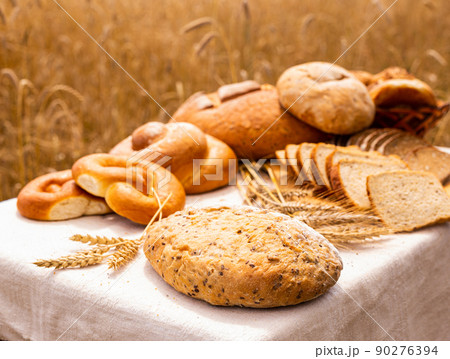 lot of different flavored bread, wheat, rye, on the table in the field outside 90276394